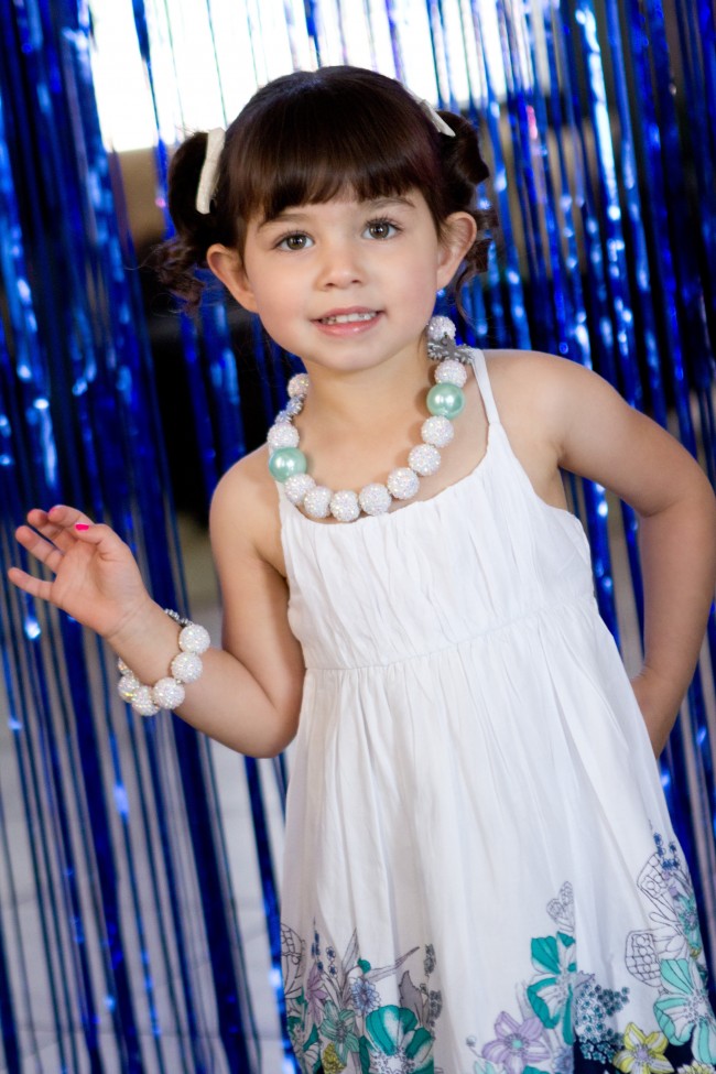 Birthday girl in front of icicle photo backdrop - Disney Frozen Birthday Party Ideas